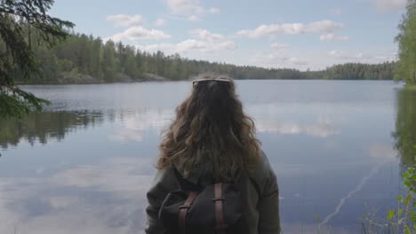 Young-Caucasian-Backpacker-Captivated-By-An-Idyllic-Lake-With-Dense-Forest-In-Finland