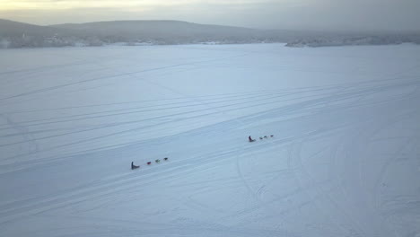 Luftaufnahme-Von-Menschen,-Die-Im-Winter-In-Schweden-Hundeschlitten-In-Kiruna-Fahren