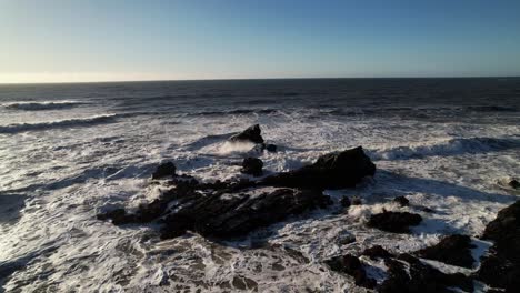 Die-Drohne-Umkreist-Während-Des-Sonnenuntergangs-Subtil-Die-Ozeanischen-Gezeitenfelsen-Am-Mavericks-Beach-In-Kalifornien