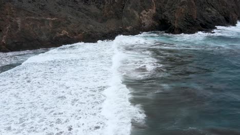 Panoramic-view-of-foamy-sea-waves-running-ashore-at-Playa-de-Sepultura,-La-Gomera,-Canary-Islands,-Spain-with-black-volcanic-sand