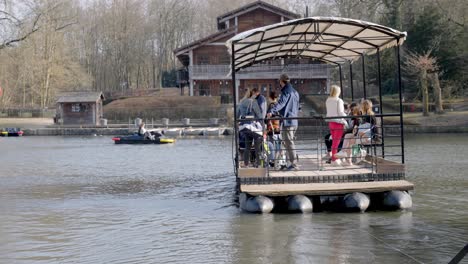 A-small-group-of-people-taking-the-ferry-across-the-pond-at-Bois-de-la-Cambre,-Brussels,-Belgium