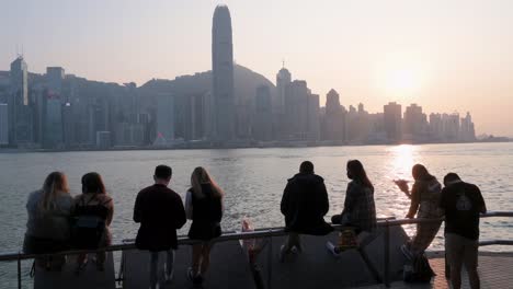 La-Gente-Se-Reúne-A-Lo-Largo-Del-Paseo-Marítimo-Del-Puerto-De-Victoria-Mientras-Disfrutan-De-La-Vista-Del-Horizonte-De-Hong-Kong-Mientras-Se-Pone-El-Atardecer