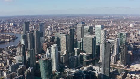 High-dolly-forward-drone-shot-into-centre-of-Canary-wharf-Towers-on-a-sunny-day