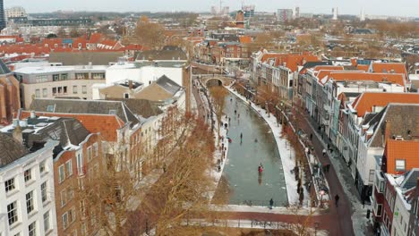 Aerial-Over-People-Ice-Skating-On-Canal-In-Utrecht-With-City-Skyline-View