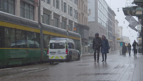 Tranvía,-Camión-De-Policía-Y-Personas-Con-Máscaras-En-La-Calle-Central-De-Una-Gran-Ciudad-En-Un-Día-De-Invierno-Frío-Y-Nevado-Durante-La-Pandemia-De-Covid