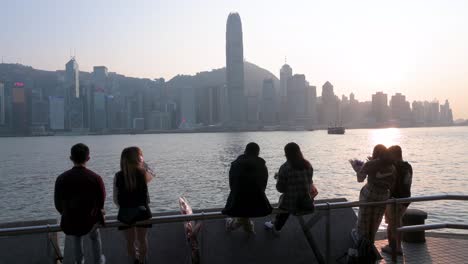 Las-Parejas-Se-Reúnen-A-Lo-Largo-Del-Paseo-Marítimo-Del-Puerto-De-Victoria-Mientras-Disfrutan-De-La-Vista-Del-Horizonte-De-La-Isla-De-Hong-Kong-Mientras-Se-Pone-El-Sol