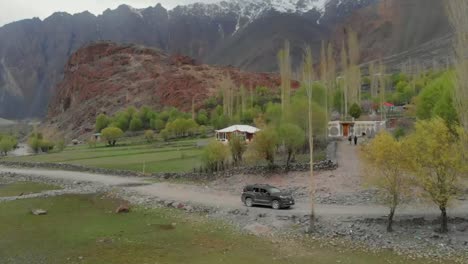 Friends-Waving-From-Parked-SUV,-Aerial-Dolly-Back-Reveal-Of-Ghizer-District-Landscape