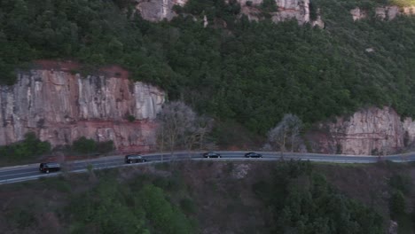 Four-Black-Cars-Driving-on-Winding-Mountain-Road,-Aerial-Tracking