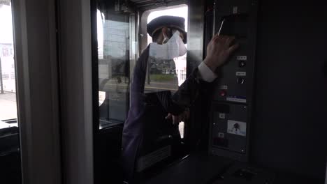 Interior-view-of-train-conductor-at-window-with-train-driving-into-station