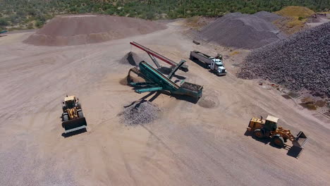 Wide-drone-shot-of-an-excavators-loading-rocks-on-a-conveyer-belt-in-a-rock-quarry