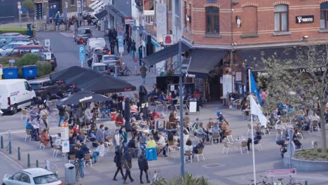 High-wide-angle-of-people-enjoying-drinks-and-snacks-at-busy-outdoor-terrace-of-bar-in