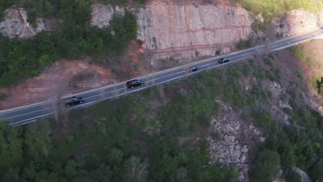 Four-Black-Cars-Driving-on-Mountain-Road,-Aerial-Tracking