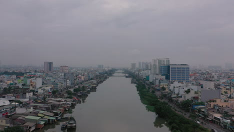 Early-foggy,smoggy-morning-drone-footage-over-canal-and-urban-waterfront-areas-of-Saigon,-Ho-Chi-Minh-City,-Vietnam