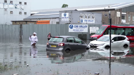 A-woman-wades-through-floodwater,-past-two-submerged-cars-and-a-red-bus-following-thunderstorms-that-saw-more-than-a-month’s-worth-of-torrential-rain-fall-in-several-hours-across-the-capital
