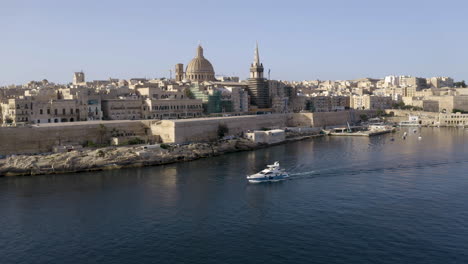 Weiße-Yacht,-Die-An-Den-Mauern-Der-Historischen-Stadt-Valletta-Vorbeisegelt,-Antenne