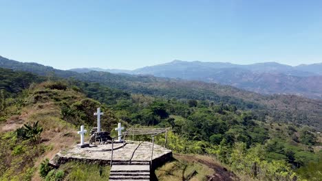 Aerial-flyover-3-white-crosses-crucifixes-in-the-remote-mountainous-landscape-of-coffee-growing-district-Ermera-in-Timor-Leste,-Southeast-Asia