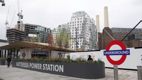 A-person-walks-into-the-new-Battersea-Power-Station-underground-station-with-the-iconic-building-and-nearby-construction-site-in-the-background