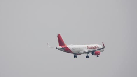 Avianca-airplane-flying-overhead-on-a-dreary-day,-pan-shot