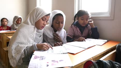 Drei-Muslimische-Schulmädchen-Lesen-Am-Schreibtisch-Im-Klassenzimmer-In-Pakistan
