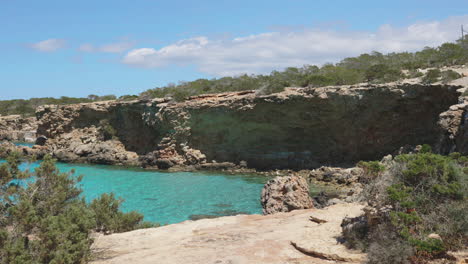 Reveal-shot-of-a-secluded-beach-in-Ibiza,-Spain,-gimbal-forward-wide-shot