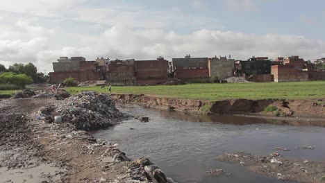 Garbage-Waste-Dumped-At-Slums-In-Pakistan,-Housing-Buildings-In-Background