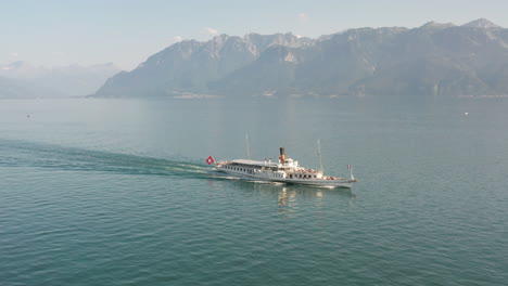 Cinematic-aerial-of-large-passenger-ship-driving-over-a-beautiful,-blue-lake