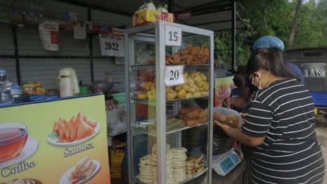 Zeitlupenaufnahme-Einer-Frau-Mit-Maske,-Die-Lebensmittel-Aus-Einem-Lokalen-Restaurant-Auf-Der-Straße-Kauft,-Weligama-Sri-Lanka