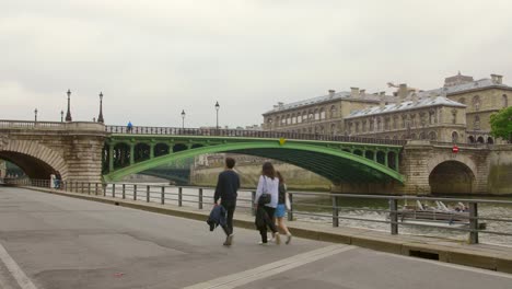 Gente-Caminando-En-La-Ruta-Libre-De-Automóviles-En-La-Orilla-Derecha-Del-Río-Sena-En-París,-Francia-Con-Pont-Notre-dame-En-Segundo-Plano