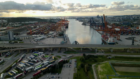 Gdynia-Internationaler-Containerhafen-Bei-Sonnenaufgang,-Parkplatz-Für-Lastwagen,-Frachter-Beim-Laden