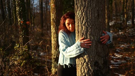 young-red-hair-caucasian-girl-hugs-a-tree-in-the-woods-at-sunset,-close-up-shot,-mother-nature-love-concept