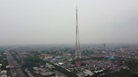 Toma-Aérea,-Una-Torre-De-Transmisión-De-Radio-En-El-Medio-De-La-Ciudad