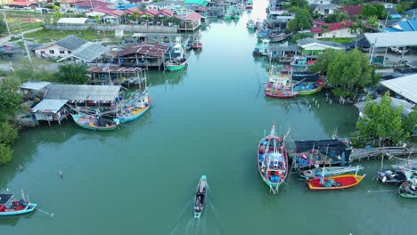 Imágenes-Aéreas-Constantes-De-Un-Pueblo-De-Pescadores-Que-Revelan-Botes-De-Pesca,-Personas-Y-Un-Bote-Que-Se-Desplaza-Río-Arriba