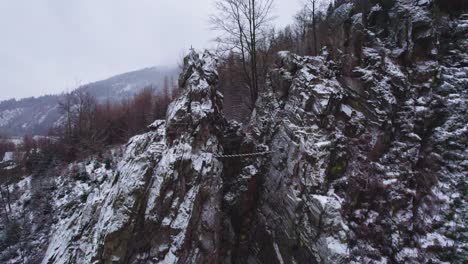 Tilt-up-view-of-famous-mountain-climbing-destination-where-climbers-climb-on-popular-steep-on-ferrata-route-called-Velká-věž-at-the-dam-called-Vír-in-czech-republic-covered-with-snow