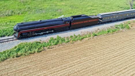 Aerial-View-of-an-Antique-Steam-Engine-and-Passenger-Coaches-Traveling-Along-Countryside-Blowing-Smoke-and-Drone-Traveling-Parallel-and-Close-To-It,-on-a-Sunny-Summer-Day