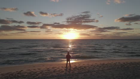 Goldener-Ozeanstrand-Sonnenaufgang-Mit-Mann-In-Kapuzenpulli-silhouette-Im-Sonnenstrahl