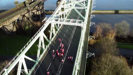 Charity-Santa-dash-fun-run-over-Runcorn-Silver-Jubilee-bridge-Aerial-view-birdseye-right-dolly