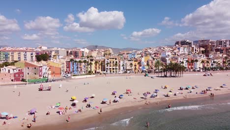 Villajoyosa,-Alicante,-Spain---Aerial-Drone-View-of-the-Sandy-Beach,-Tourists-and-Colorful-Houses-at-the-Boulevard