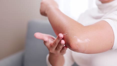 Detail-of-woman-giving-pain-reliever-cream-on-her-elbow-due-to-pain-during-arm-movement