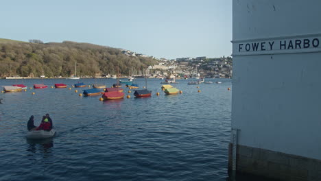 Menschen-Im-Motorboot-Kehren-Von-Segelbooten-An-Land-Zurück,-Die-Im-Hafen-Von-Fowey,-Cornwall,-England,-Großbritannien,-Festgemacht-Sind---Langsam-Herauszoomen