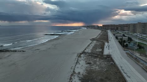 An-aerial-view-over-a-quiet-beach-in-Arverne,-NY-as-rain-falls-in-the-distance-on-a-cloudy-evening