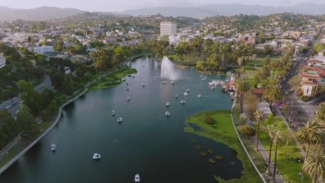 Aerial-Shot-of-Echo-Park-Lake-on-Sunny-Day-in-Los-Angeles,-Drone-Over-Fountain-and-White-Swan-Boats