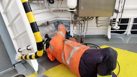 Industrial-worker-using-electric-grinder-during-changing-of-steel-hull-plates-on-ships-side---Static-handheld-from-Norwegian-ferryboat