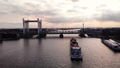 Aerial-View-From-Stern-Of-Salute-Cargo-Container-Ship-Approaching-Spoorbrug-Railway-Bridge-Along-Oude-Maas