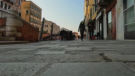 Low-angle-ground-surface-pov-of-waterfront-Fondamenta-Dei-Ormesini-and-people-walking,-Venice-in-Italy