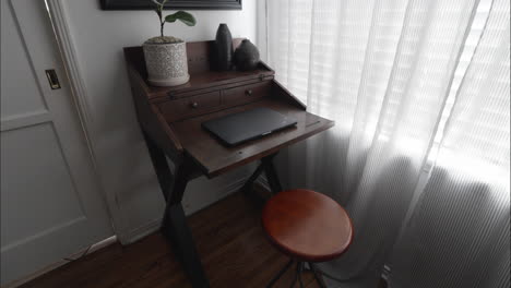 Modern,-clean-home-office-with-decor,-plants,-mirror-and-closed-laptop-on-desk