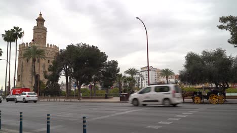 Street-level-view-towards-famous-Torre-del-Oro-in-Seville,-Spain-with-car-traffic