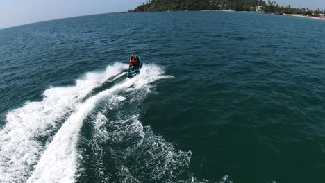 Tracking-Shot-Of-Excited-Couple-Drifting-Jet-Ski-In-High-Speed-Towards-Beautiful-Green-Island,-Sri-Lanka
