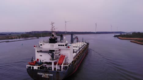 Aerial-Flying-Behind-Stern-Of-Pacific-Fortune-Cargo-Ship-Along-Oude-Maas-On-Cloudy-Day