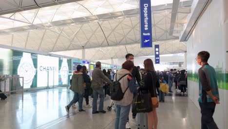 Passengers-take-photos-in-front-of-the-departure-hall-and-sign-at-Chek-Lap-Kok-International-Airport-in-Hong-Kong,-China