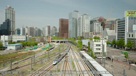 KTX-Fast-Passenger-Train-Arrives-at-Seoul-Station-Depot,-City-Skyline-Panorama-Against-Blue-Sky